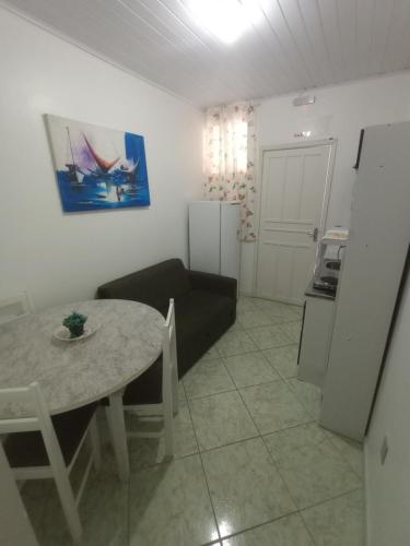 a kitchen and a living room with a table and a couch at Hospedagem 4Lm in Penha