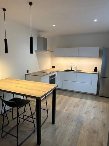 une cuisine avec une table en bois et une table et des chaises dans l'établissement Appartement Brignais Centre en face du pont romain, à Brignais