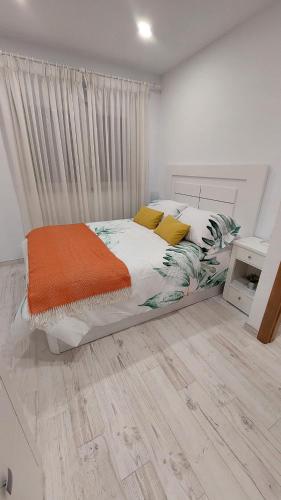 a white bedroom with a bed with an orange blanket at AGRO da FONTE- Apartamento in Muros