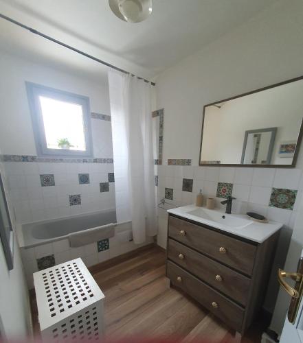 a bathroom with a sink and a mirror and a tub at Le Temps d'une Pause in Andert-et-Condon