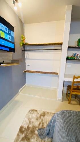 a living room with a tv and a bed and a couch at Studio Terra Nova in Itumbiara