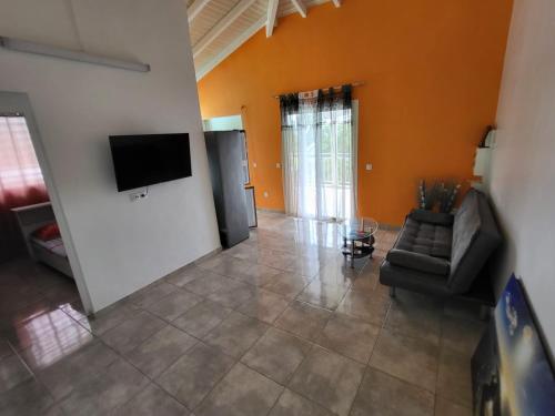 a living room with a couch and a flat screen tv at Appartement Multipliant in Deshaies