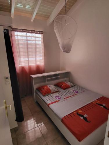 a small bed in a room with a red curtain at Appartement Multipliant in Deshaies