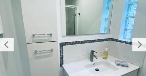 a white bathroom with a sink and a mirror at Maison d'hôtes La Capucine in Le Pontet
