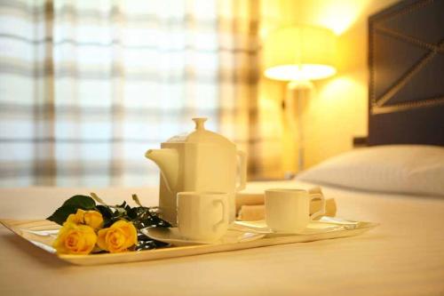 a tea set on a tray with two cups and roses at Hotel Cristallo in Giulianova