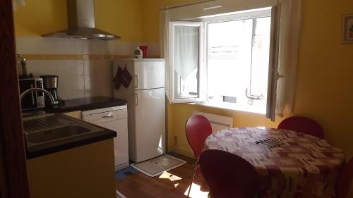 une cuisine avec une table, un évier et une fenêtre dans l'établissement Vent de Terre, à Audierne