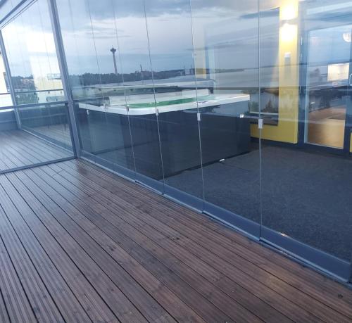 an empty office with glass walls and a wooden floor at TAMPERE PENTHOUSE-tasokas moderni kaupunki huoneisto huipulla -ISO JACUZZI omalla KATTOTERASSILLA - AURINKOTUOLIT ja Aurinko odottaa Sinua - huikea maisema- - 10 HLÖ - free parking in Tampere