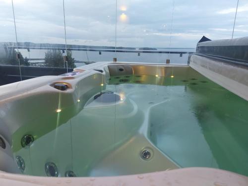a bath tub filled with water next to a window at TAMPERE PENTHOUSE-tasokas moderni kaupunki huoneisto huipulla -ISO JACUZZI omalla KATTOTERASSILLA - AURINKOTUOLIT ja Aurinko odottaa Sinua - huikea maisema- - 10 HLÖ - free parking in Tampere