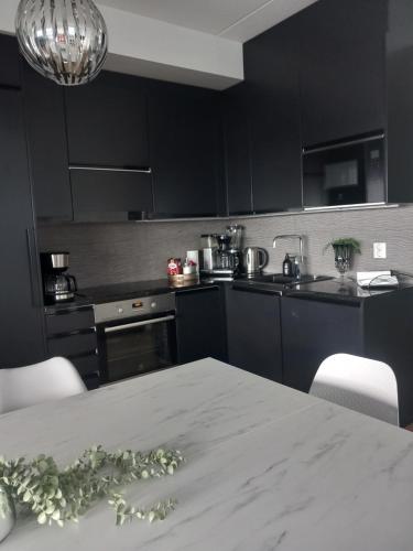 a kitchen with black cabinets and a table with flowers on it at TAMPERE PENTHOUSE-tasokas moderni kaupunki huoneisto huipulla -ISO JACUZZI omalla KATTOTERASSILLA - AURINKOTUOLIT ja Aurinko odottaa Sinua - huikea maisema- - 10 HLÖ - free parking in Tampere