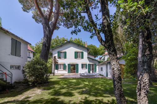 widok na biały dom z zielonymi okiennicami w obiekcie Grande villa - 50m plage - piscine - proche centre gare - parking w Arcachon