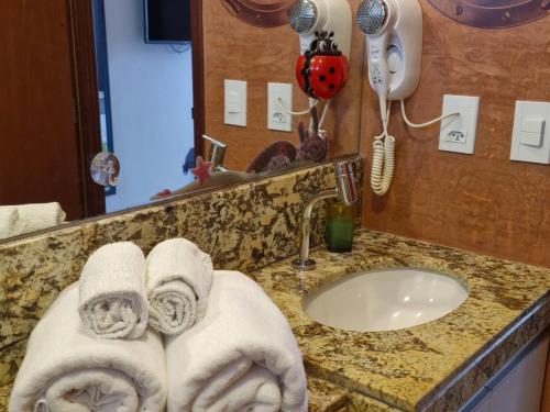 a bathroom with towels on a counter and a sink at Hotel Natal Plaza com piscina, academia, 100m da praia de Ponta Neg in Natal