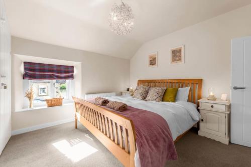 ein Schlafzimmer mit großem Bett und Fenster in der Unterkunft Fable Cottage Luxurious Stay in Bakewell