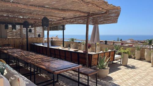 a patio with tables and chairs with a view of the ocean at Monza Surf House in Tamraght Ouzdar