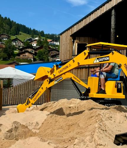 a yellow excavator working in a pile of sand at Ferienwohnung Brunni-Lodge am Grossen Mythen in Alpthal