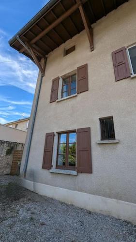 a building with brown doors and windows on it at La poule house in Hostun