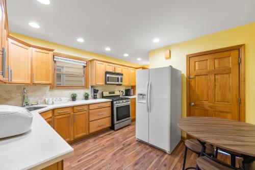 a kitchen with wooden cabinets and a white refrigerator at Epic Spa & Play Retreat NYC EWR Sleeps 30! in Bayonne