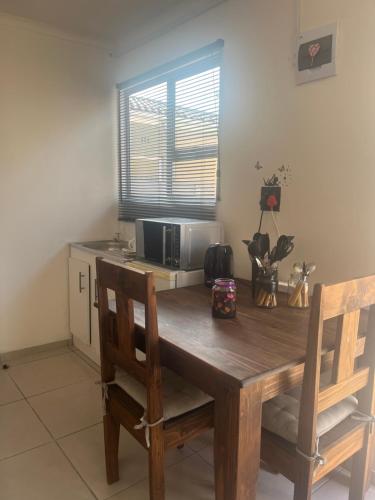a dining room table with two chairs and a microwave at Relaxa Sleep & Go - Self Catering Accommodation in Cape Town