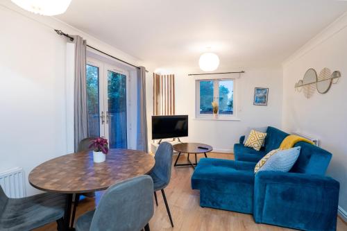 ein Wohnzimmer mit einem blauen Sofa und einem Tisch in der Unterkunft Beautiful 2-Bed City Centre Apartment with Balcony in Milton Keynes