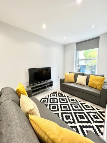 a living room with a couch and a tv at WOW Abbey Road Apartment - Sleeps up to 8 in London