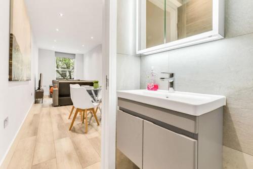 a white bathroom with a sink and a table at WOW Abbey Road Apartment - Sleeps up to 8 in London