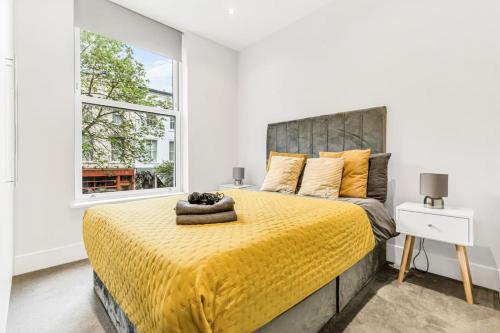 a bedroom with a large bed with a yellow bedspread at WOW Abbey Road Apartment - Sleeps up to 8 in London