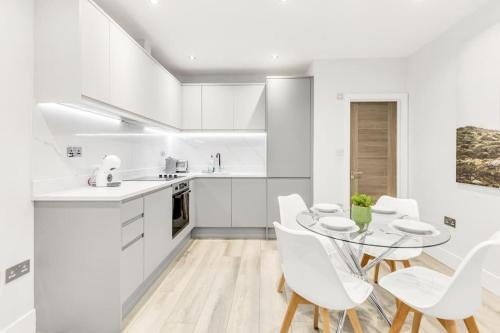 a kitchen with white cabinets and a table and chairs at WOW Abbey Road Apartment - Sleeps up to 8 in London