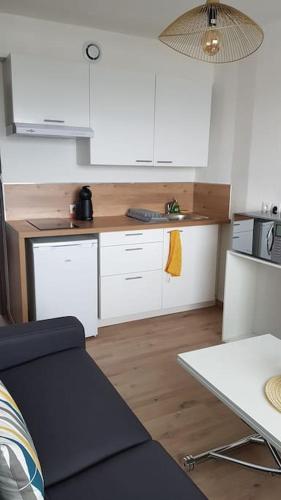 une petite cuisine avec des armoires blanches et une table dans l'établissement Egat font-romeu Appartement 2ème étage, à Égat