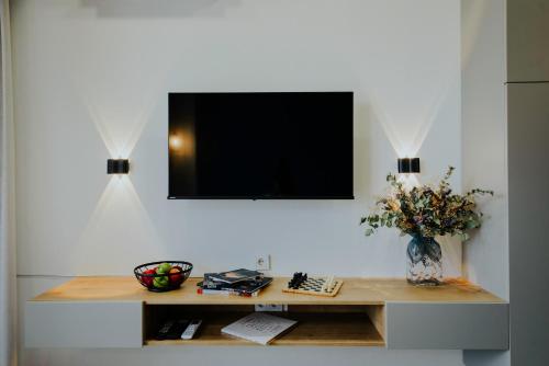 a desk with a television on a wall with a vase of flowers at Pool House in Tbilisi City
