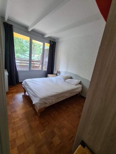 une chambre avec un lit et une grande fenêtre dans l'établissement Praloup 1600 ideal famille, à Uvernet