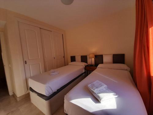 Zimmer mit 2 Betten und einem Buch auf dem Tisch in der Unterkunft APARTAMENTO DUPLEX con piscinas y MARAVILLOSAS VISTAS AL MAR in Estepona