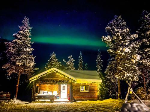 a cabin with the northern lights in the sky at Aurora Camp Kurravaara in Kurravaara
