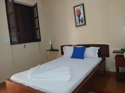 a bedroom with a bed with a blue pillow on it at Pensao Mille Nuits in Tarrafal