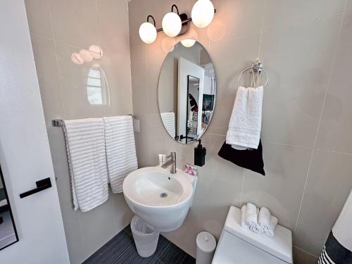 a white bathroom with a sink and a mirror at Ocean Drive Oasis in Art Deco District of South Beach in Miami Beach