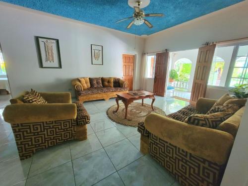 a living room with couches and a ceiling fan at Green's Palace Jamaica in Oracabessa