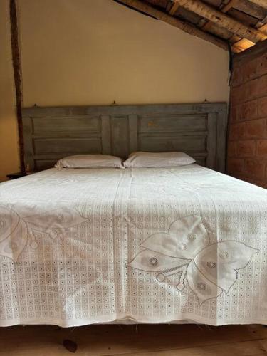 un letto con copriletto bianco e 2 cuscini di Vila do Salitre - Chalé a 5 min de lagos e cachoeiras a Diamantina