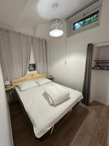 une chambre avec un lit avec des draps blancs et une fenêtre dans l'établissement Le refuge thermal, à Luchon