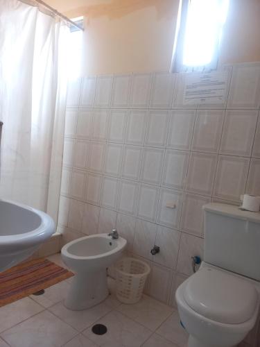 a white bathroom with a toilet and a sink at Pensao Mille Nuits in Tarrafal