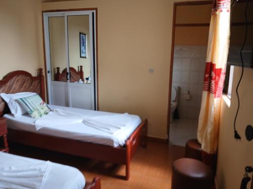 a bedroom with two beds and a bathroom with a shower at Pensao Mille Nuits in Tarrafal