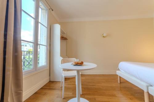 Cette chambre comprend une table, un lit et une fenêtre. dans l'établissement La Suite Victor Hugo, à Paris