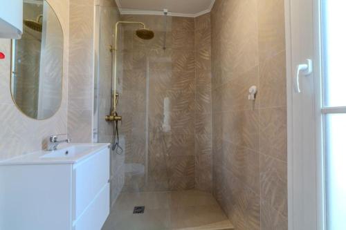 une salle de bain avec une douche avec un lavabo et un miroir dans l'établissement La Suite Victor Hugo, à Paris