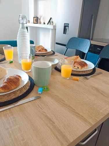 une table avec des assiettes de nourriture et des verres de jus d'orange dans l'établissement 4pers Wifi Netflix Prox Lille-métro-tram, à Roubaix