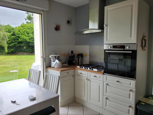a kitchen with white cabinets and a stove top oven at Kernay, grande maison familiale pour 10 personnes in Lannion