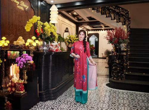 a woman is standing in a room with flowers at Thuy Duong Boutique Hotel Hue in Hue
