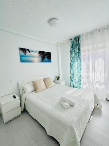 a white bedroom with a large white bed and a window at Apartamento en Santander in Santander