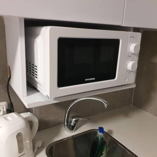 a microwave above a kitchen sink with a kitchen counter at Ryo 18 דירה במלון בוטיק 2 דקות מטיילת בת ים in Bat Yam