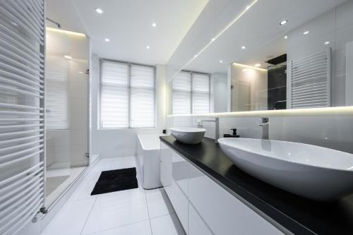 Baño blanco con dos lavabos en una encimera negra en White Luxury Apartment, en Katowice