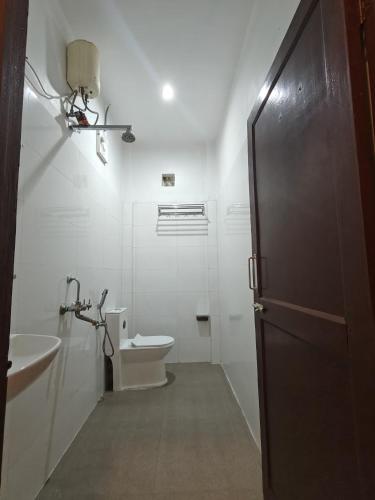 a white bathroom with a toilet and a sink at Yerrata Resorts in Havelock Island