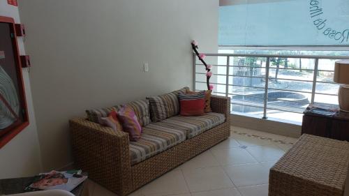 a couch with pillows sitting in a room with a window at Hotel Rosa da Ilha Guaruja - Perto do Mar com piscina in Guarujá