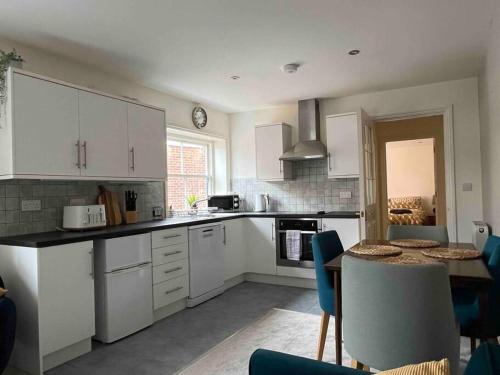 Una cocina con gabinetes blancos y una mesa con sillas. en Town centre apartment with parking, en Wallingford