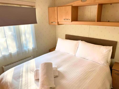 a small bedroom with a bed with towels on it at Anchor's Drop in Blue Anchor